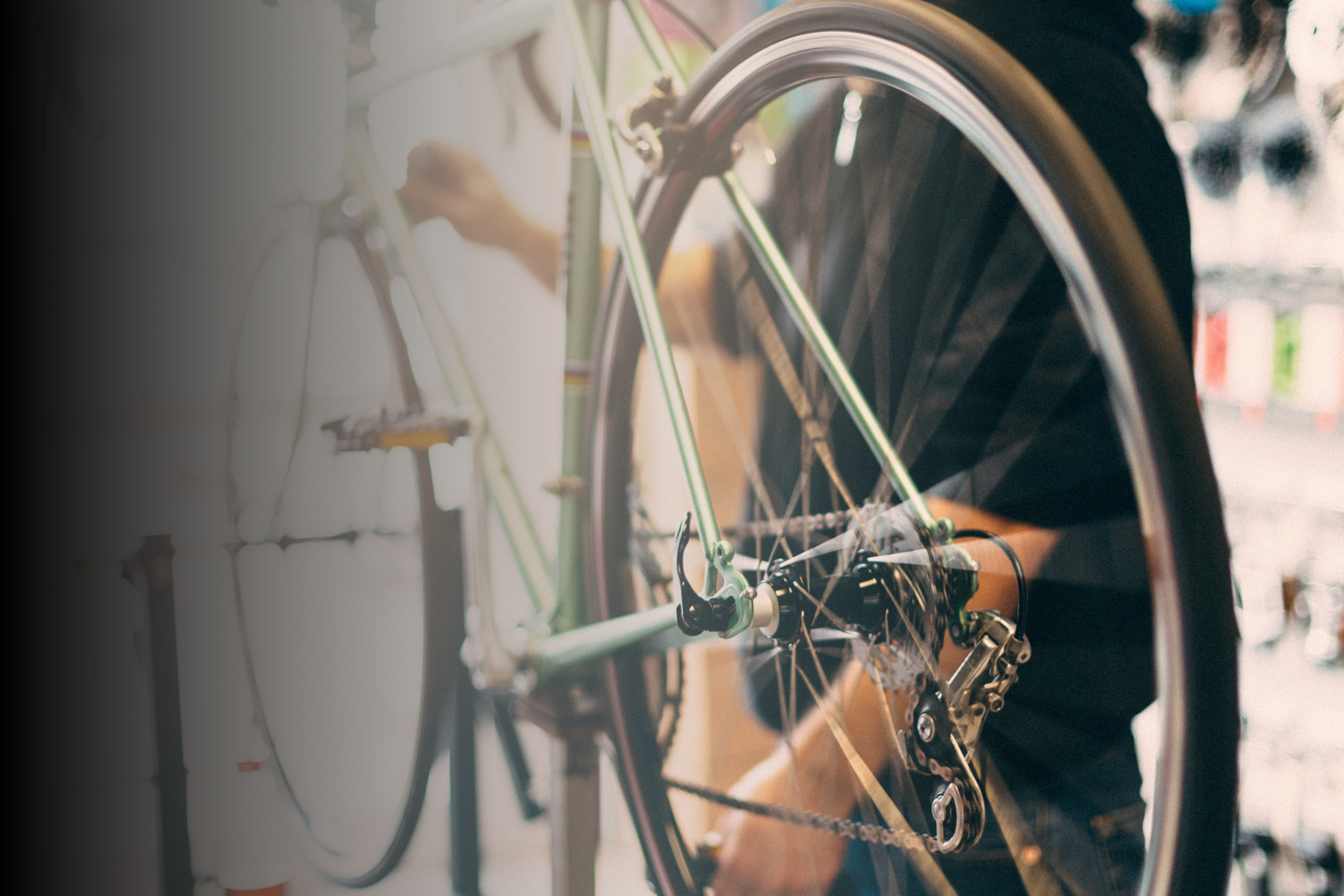 Hero image with bike shop associate adjust wheels on mounted bike