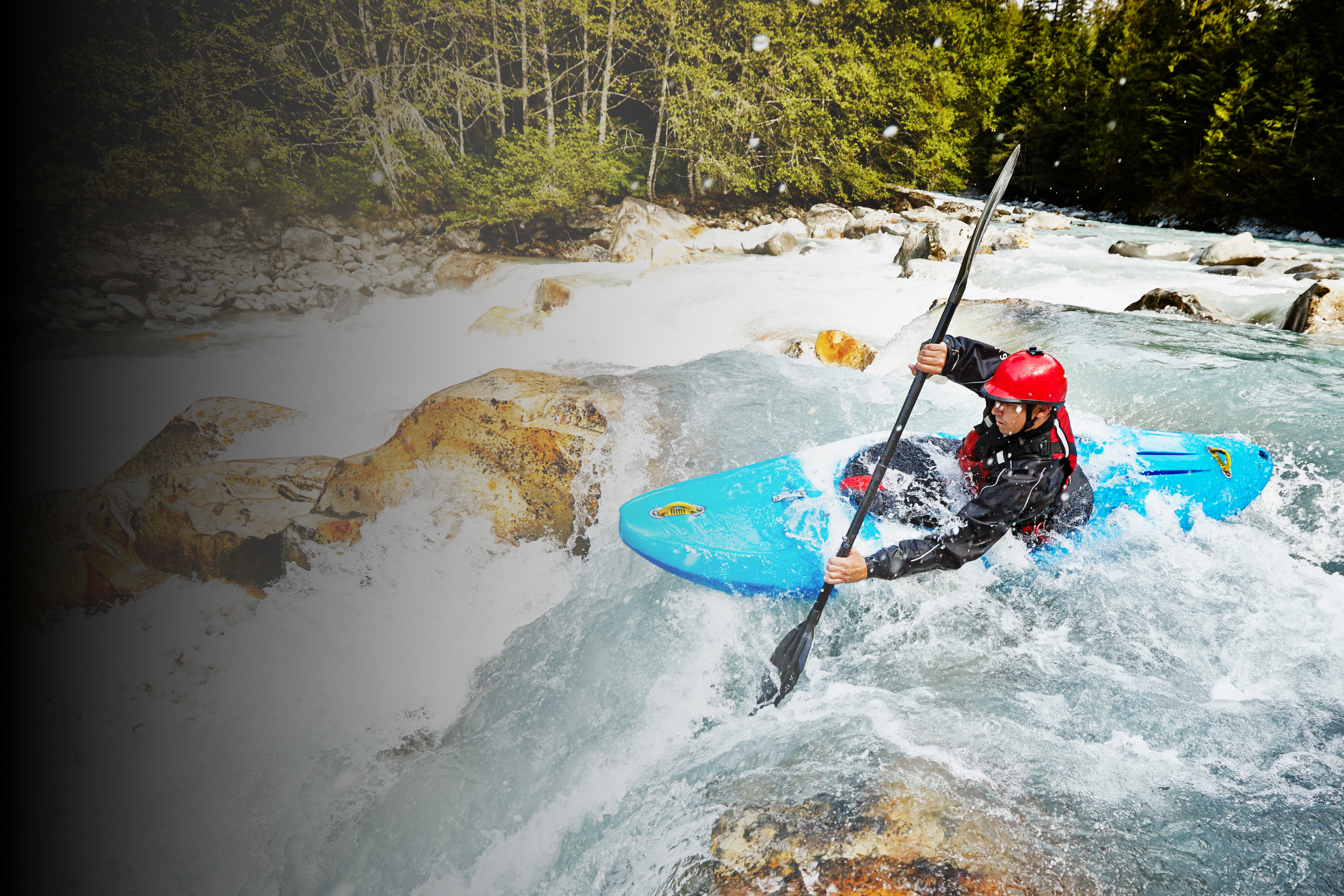 Man paddles a rapid on the river in a blue white water kayak