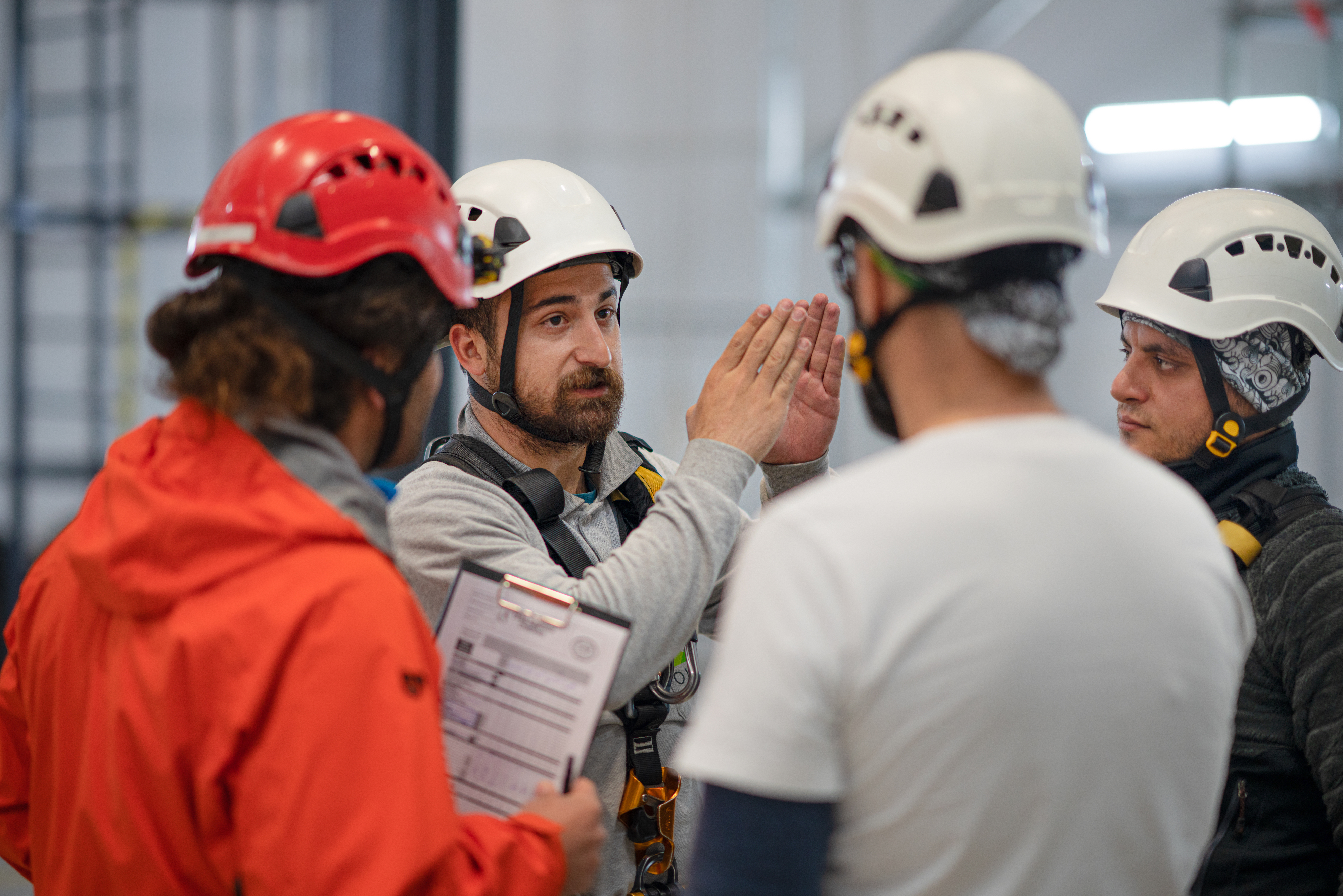 Group of men in climbing gear gathered around a safety instructor discussing safety protocols 