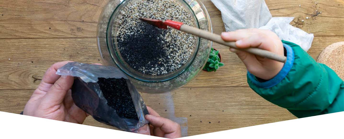 hands filling glass jar with small rocks