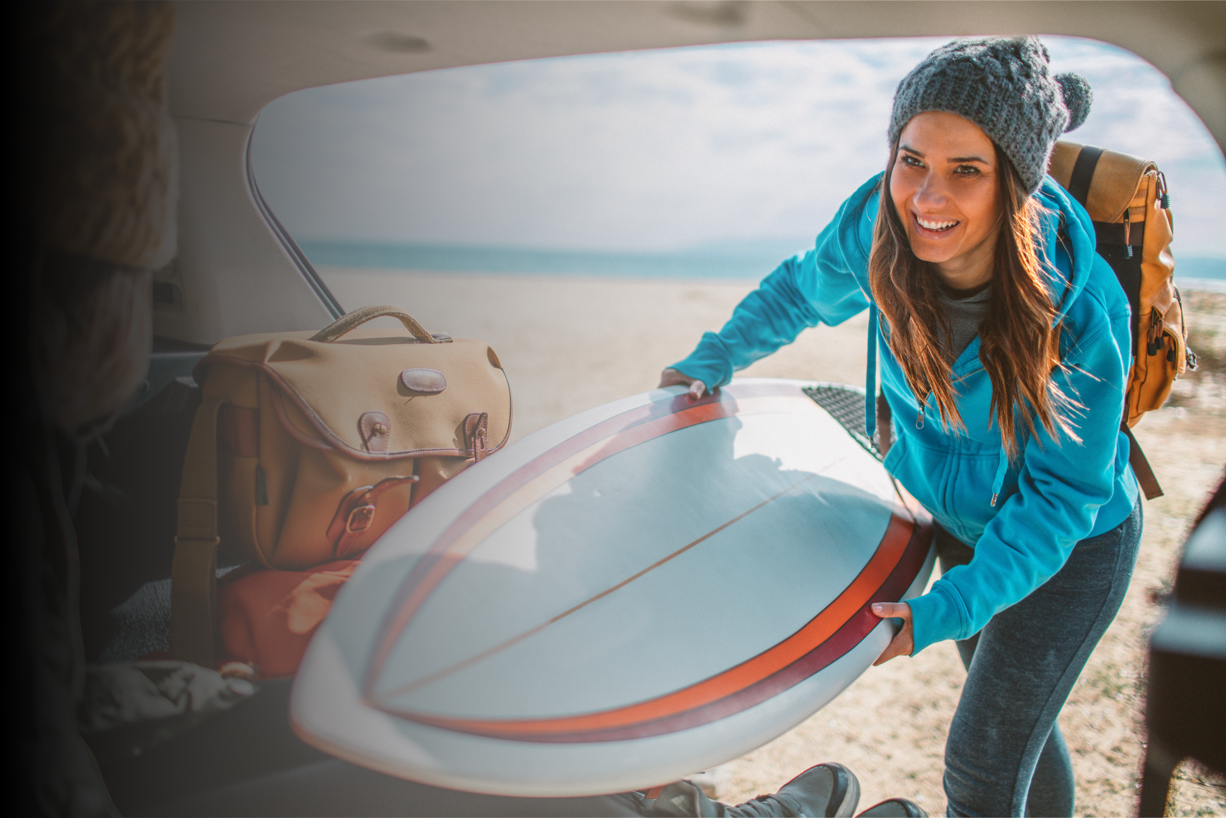 Female surfer packs car with surfboard and gear 