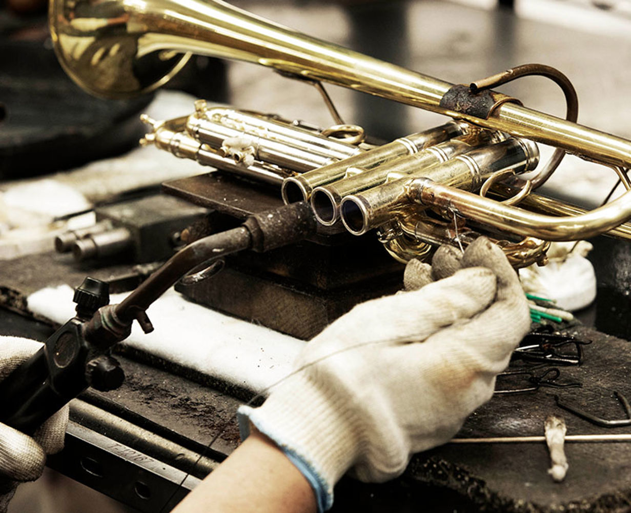 Bach employee working on a trumpet.